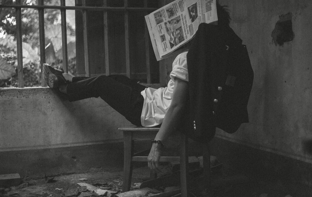 Young Danish man reading a newspaper at a cafe table